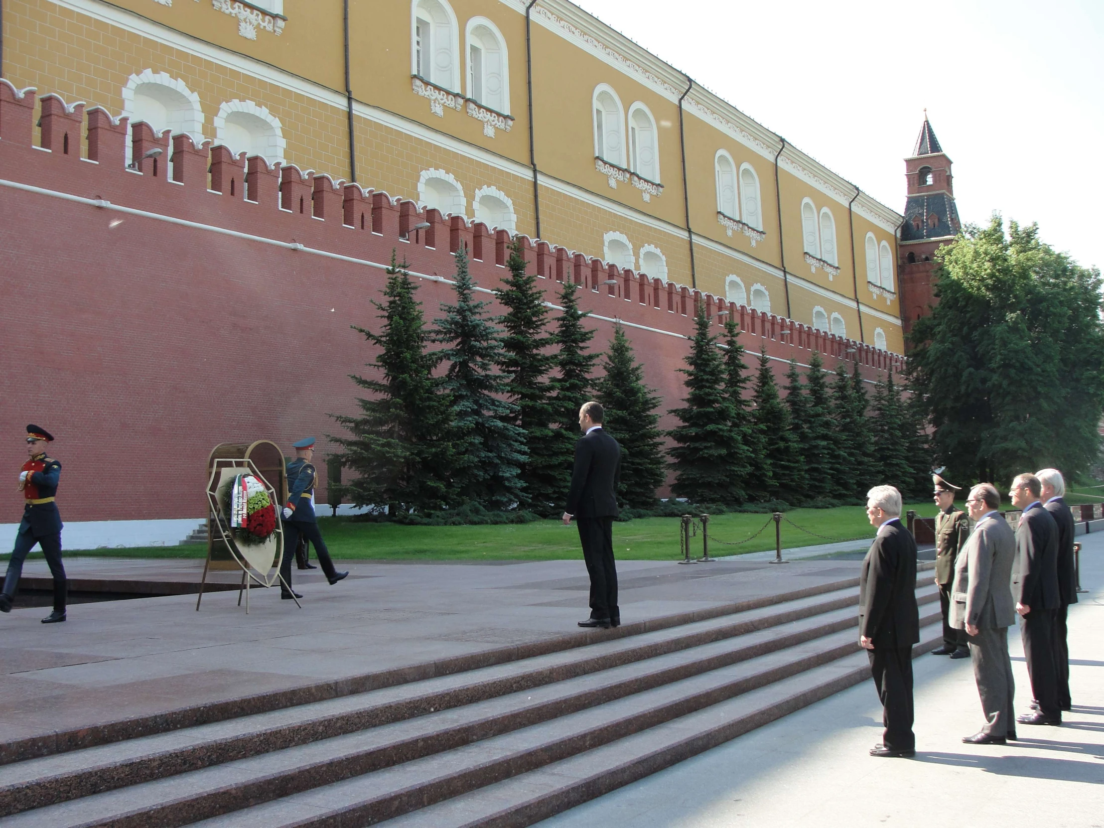 group of men standing on steps next to wall in front of building