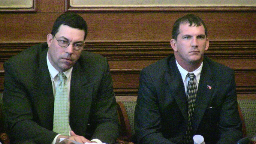 two men in suits are sitting at a table