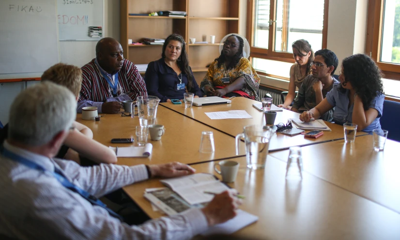 a group of people sitting around a table having a meeting