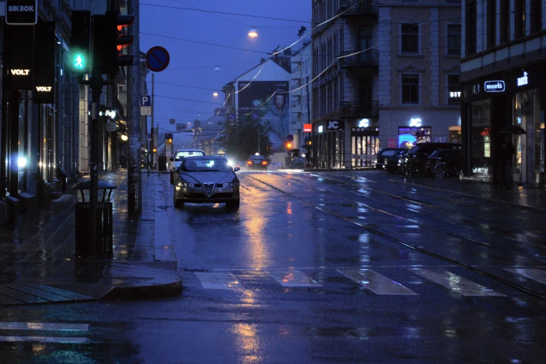 a car driving down a rain soaked city street