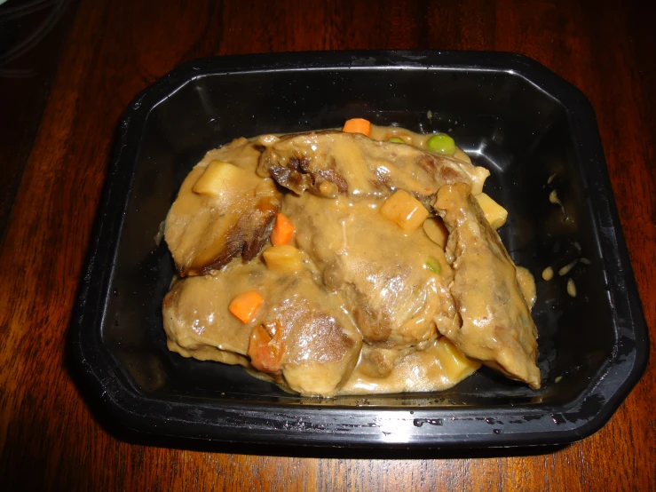 food in a black container on a table