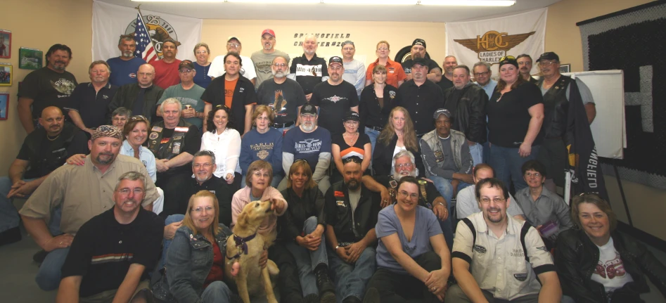 large group of people with hats and pet dogs pose for picture