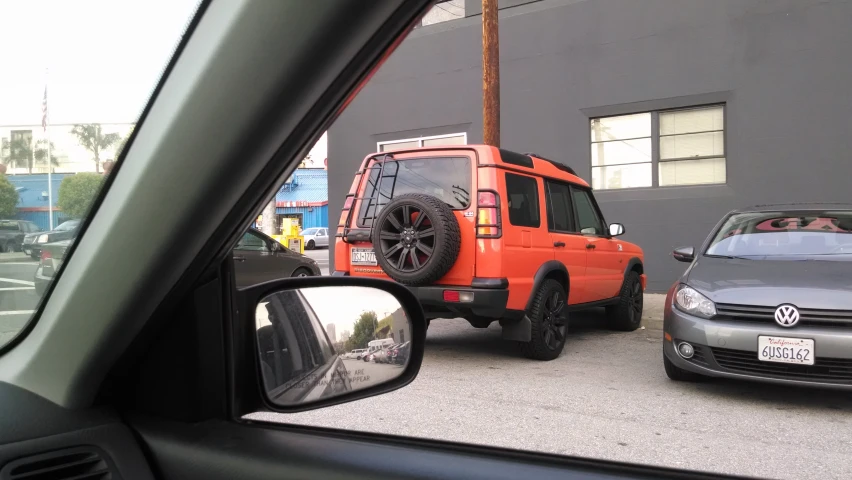 orange vehicle parked on the street next to silver car