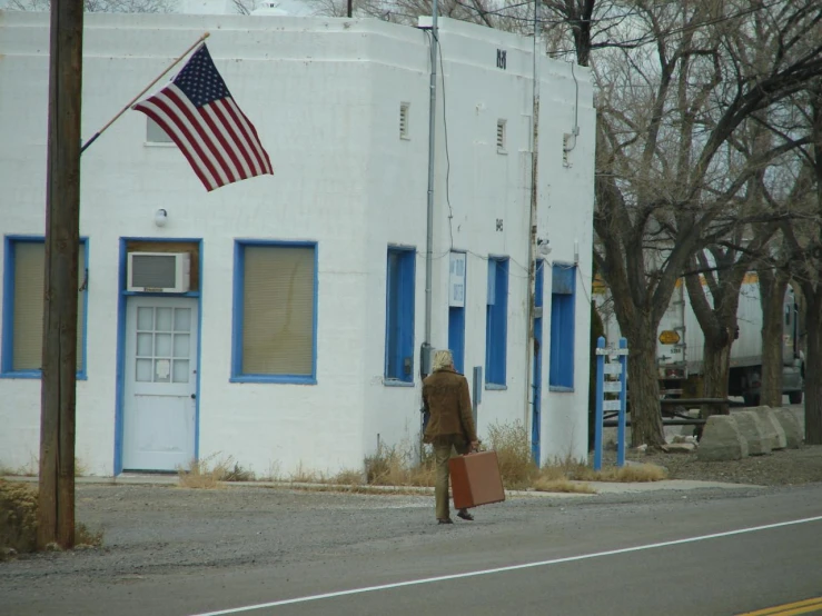a man carries a bag down the street while standing near an american flag