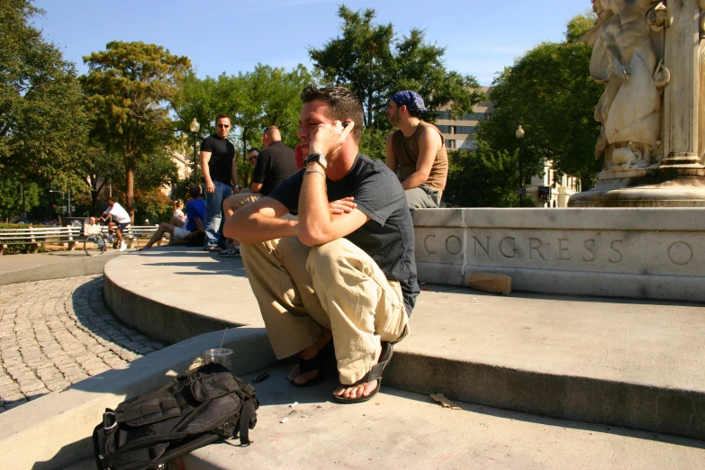 a man sitting on a curb talking on a phone