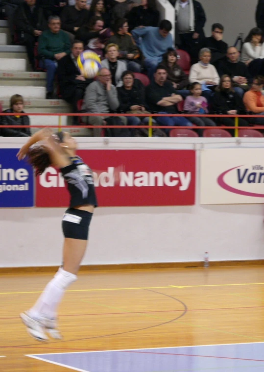 a woman is playing volleyball as a crowd watches