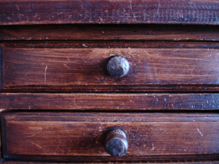 a wooden dresser has rivets on the bottom and a drawer that is slightly down
