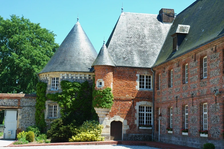 a brick building with two towers and ivy growing on it