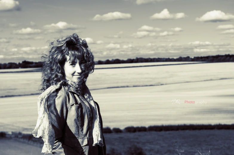 a woman with curly hair standing on the edge of a cliff