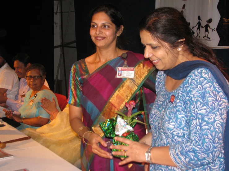 women smiling and standing next to a long table