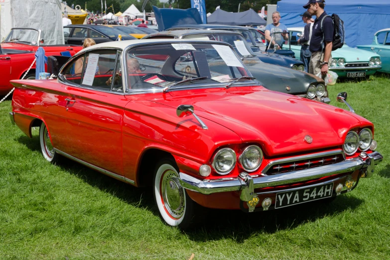 a vintage car parked at a show with several other old cars