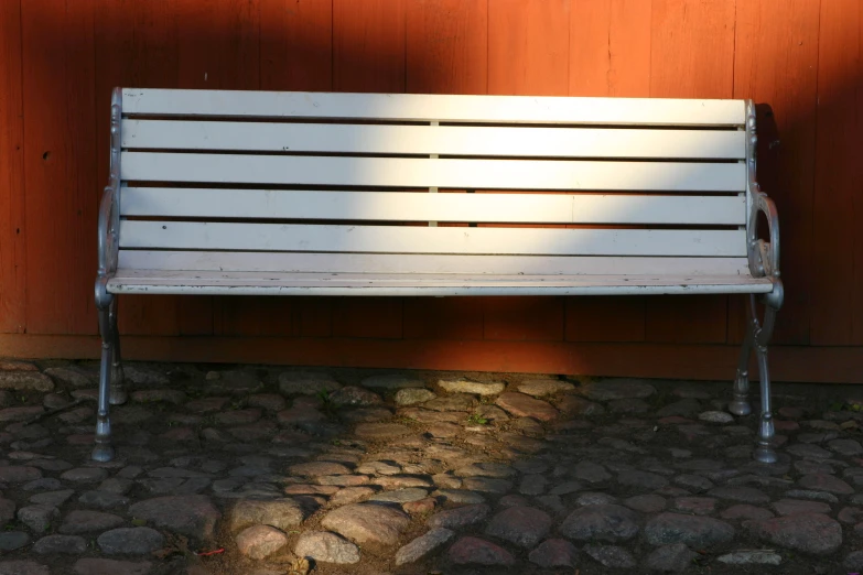 an empty bench against a brown building