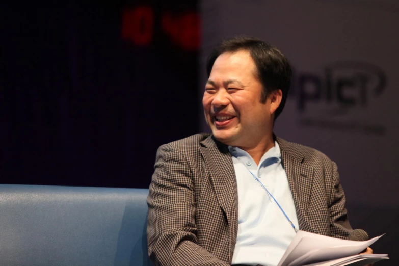 a smiling man sitting on a blue couch