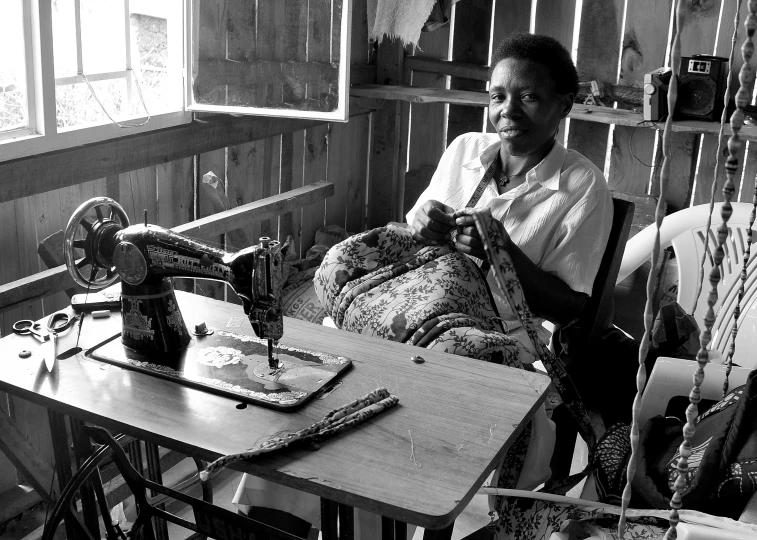 the woman smiles as she sews on an old singer's sewing machine