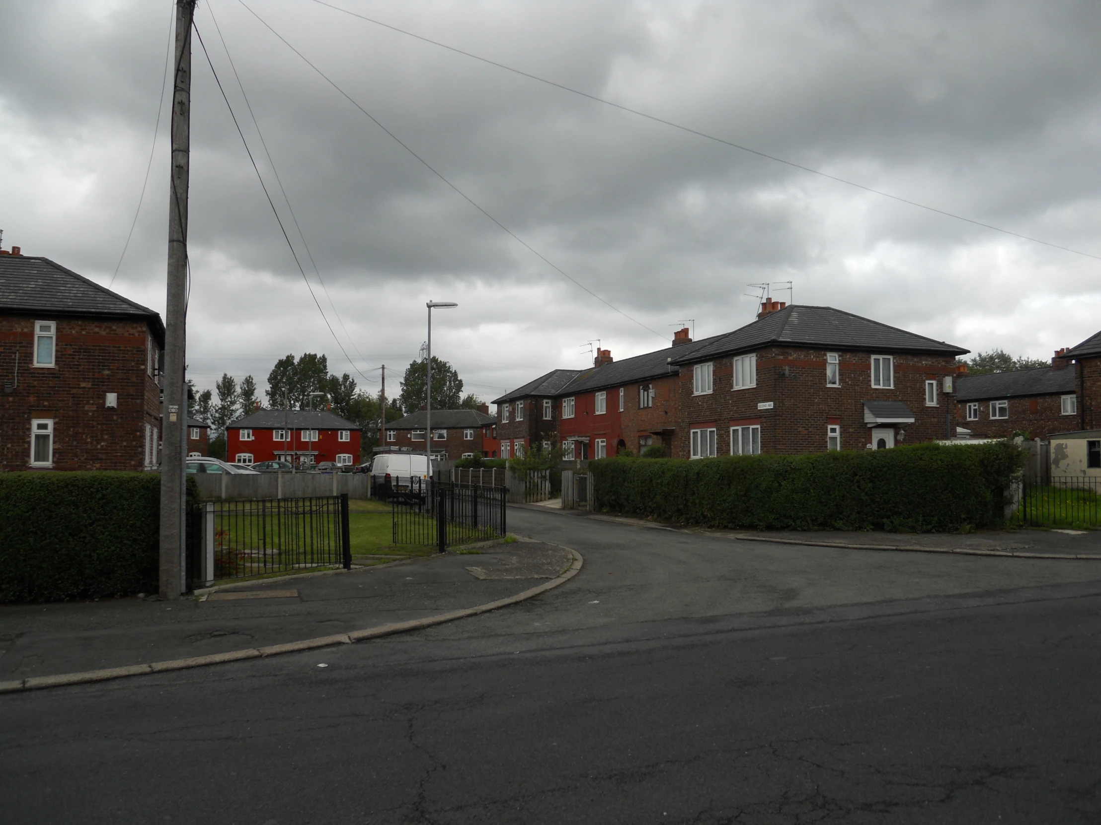 a residential street surrounded by brick houses under cloudy skies