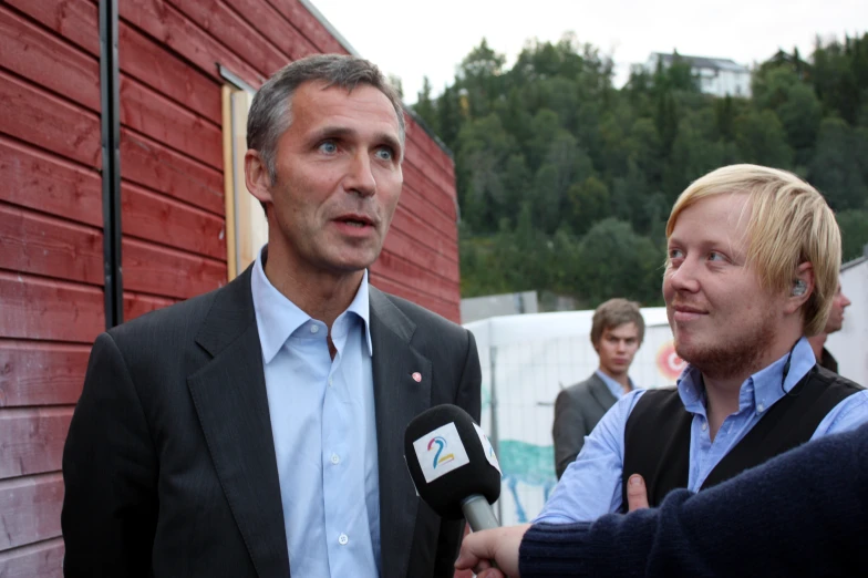 man standing and talking to a reporter outside