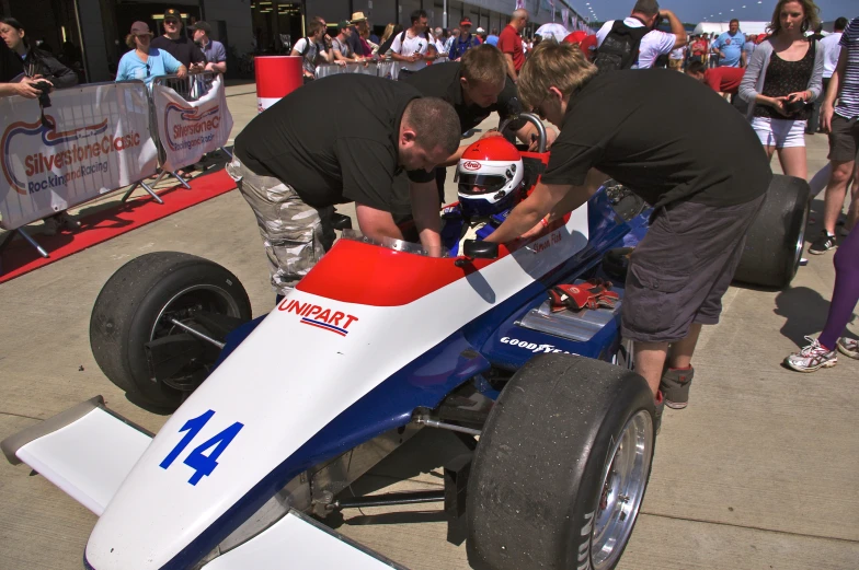 people inspecting and looking at a race car on display