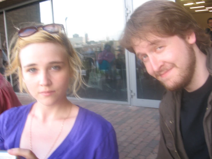 a man and woman posing outside on a sunny day