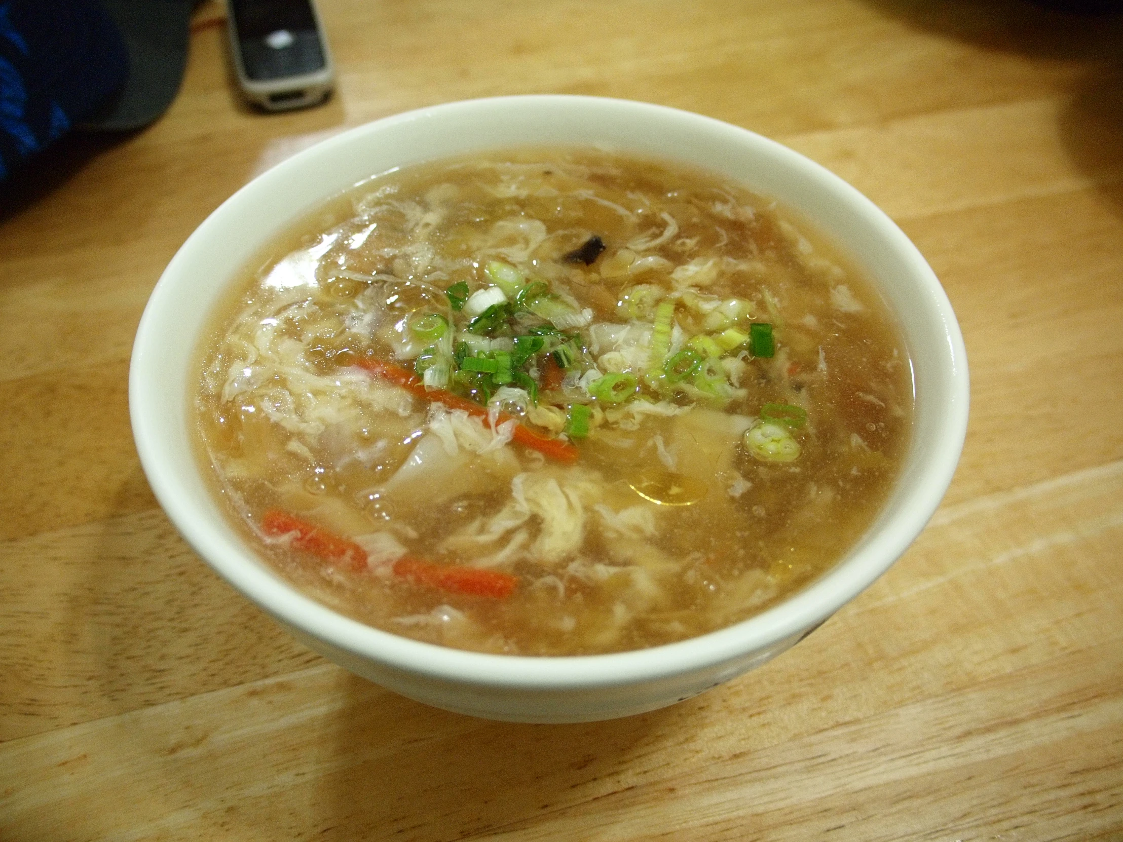 a bowl of soup sits on a wooden table