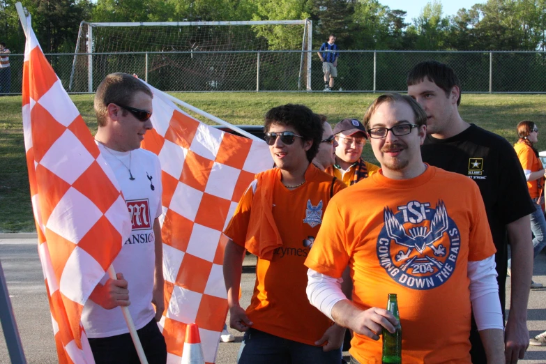 people on a field holding two checkered orange and white flags