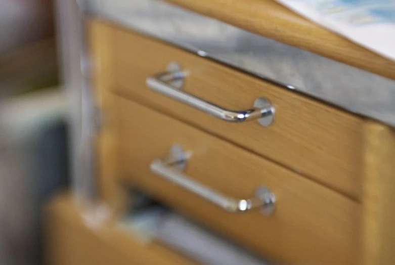 a wooden drawer with metal handles and a book on top