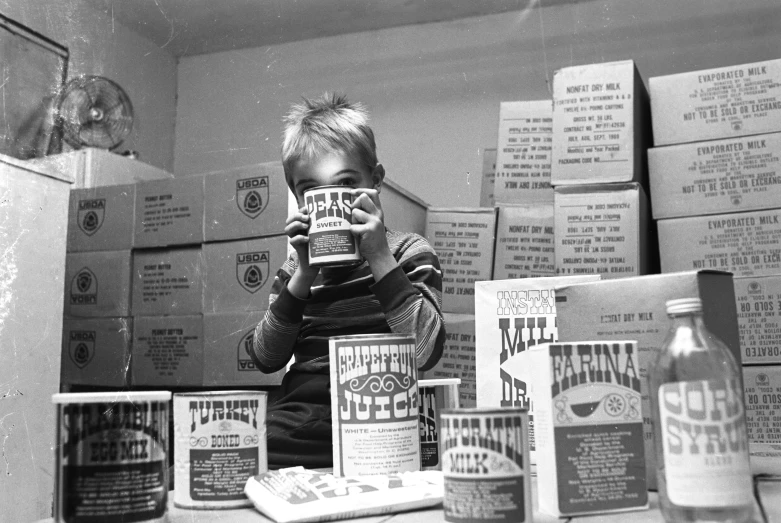 a little boy standing in front of boxes looking at bottles