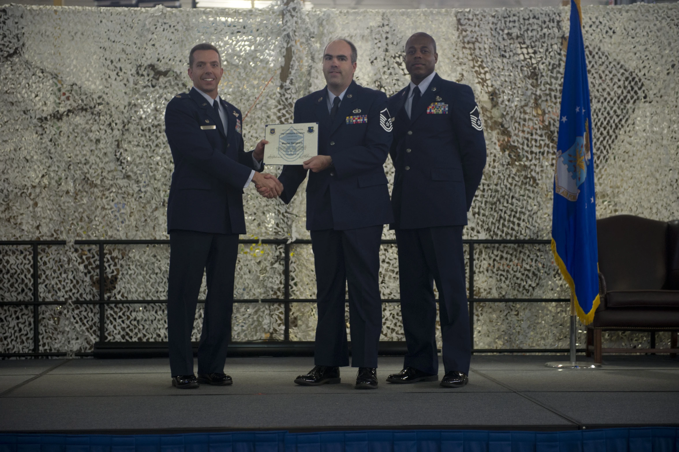 three men are dressed in blue, while one holds an award