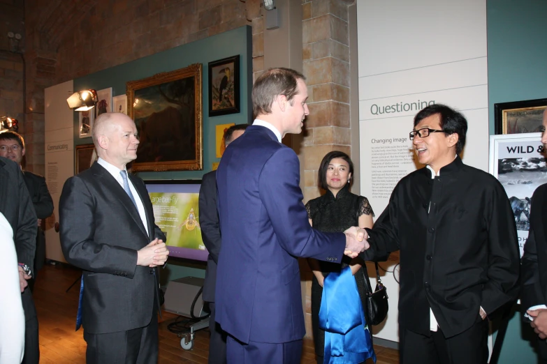 two men and one woman are shaking hands with a man in a suit