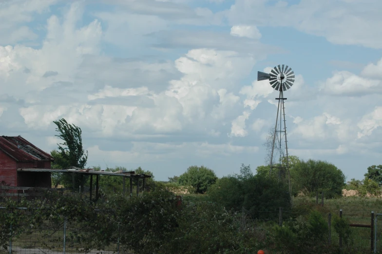 a windmill and other farm buildings near a field