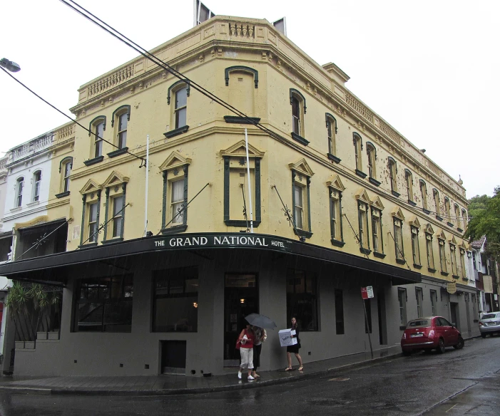 two people with an umbrella stand in front of a tan building