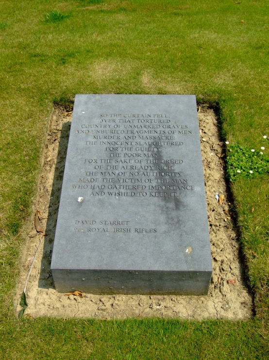 a granite tombstone sits in a grassy area