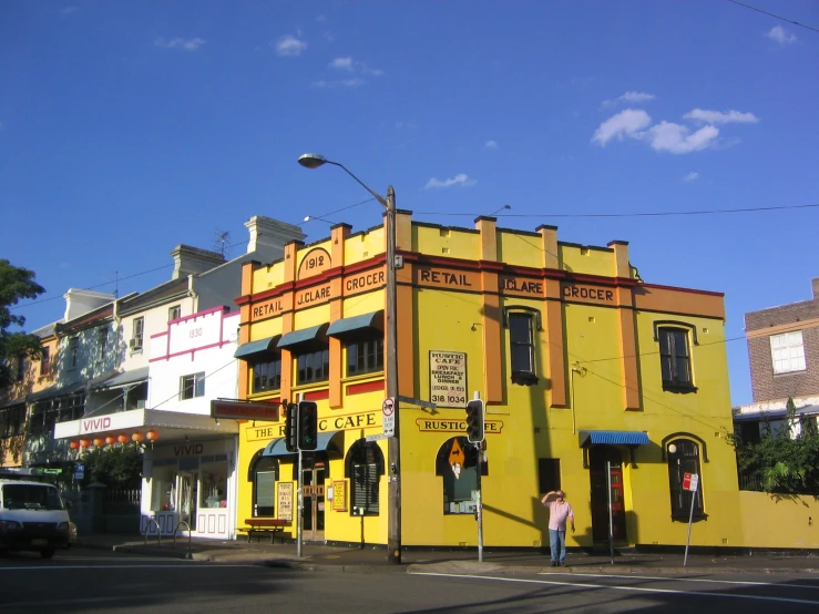an old building that is painted yellow and has two stories, the front of it is on a street corner in front of the other buildings