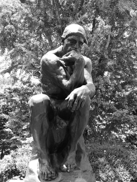 a statue in front of trees with a forest behind it