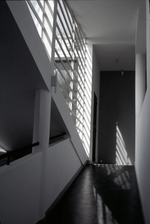 a long hallway with a wooden floor next to a stairwell