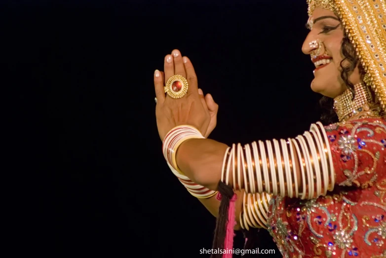 a woman with red and gold jewelry wearing rings