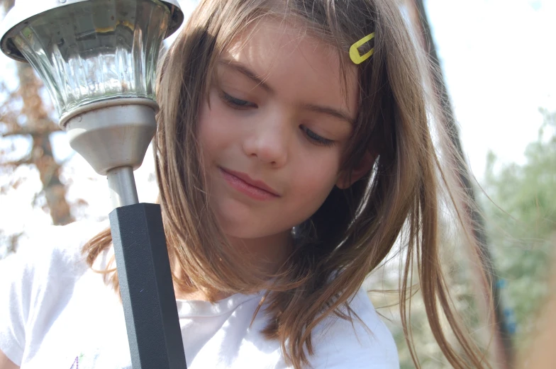 a girl with long hair standing holding onto a lamp