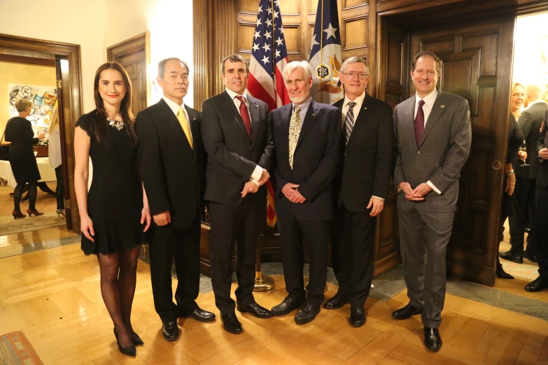 a group of people posing for a pograph with flags and suits