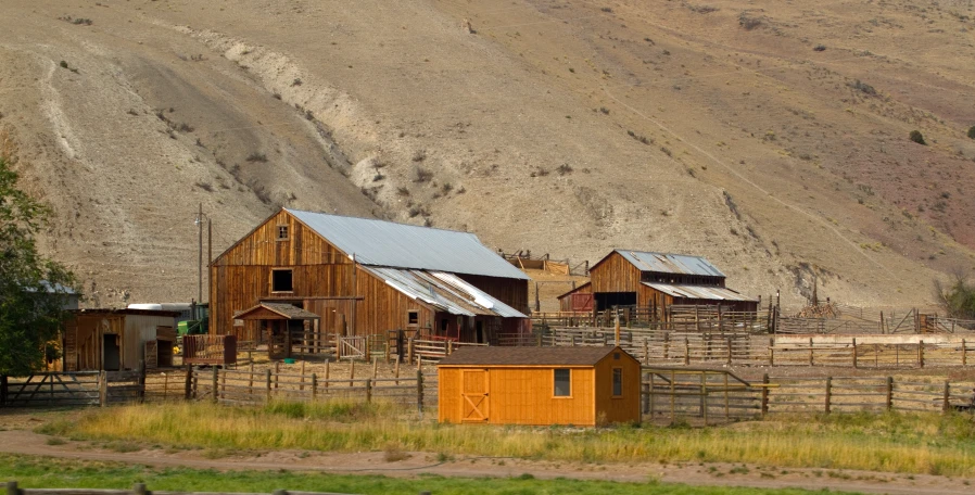 a group of buildings sitting near a hill in the country