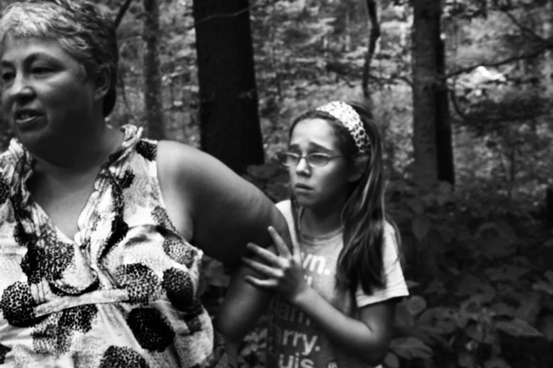 a mother and daughter holding a frisbee in the woods