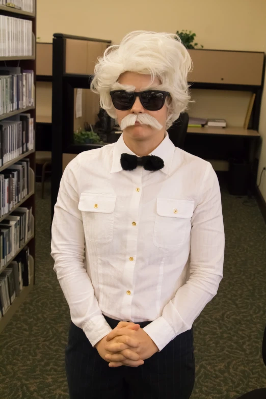 a person with white hair and glasses has a fake mustache on his head