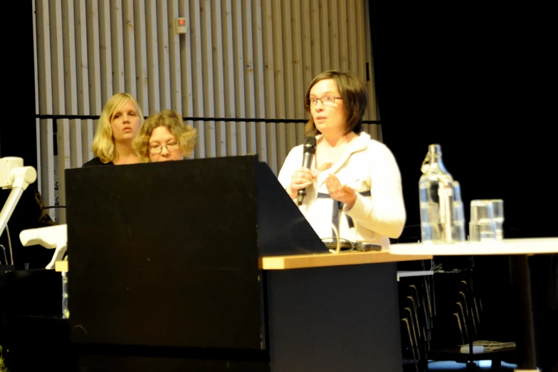 three women talking behind a podium at an event