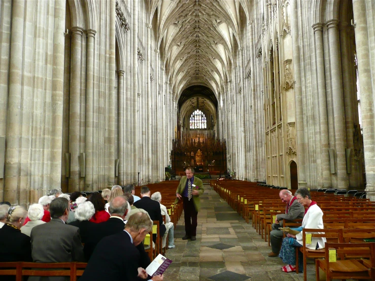 a man is praying in a church while others sit on benches