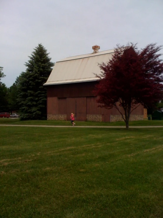 two children running through a field towards a barn