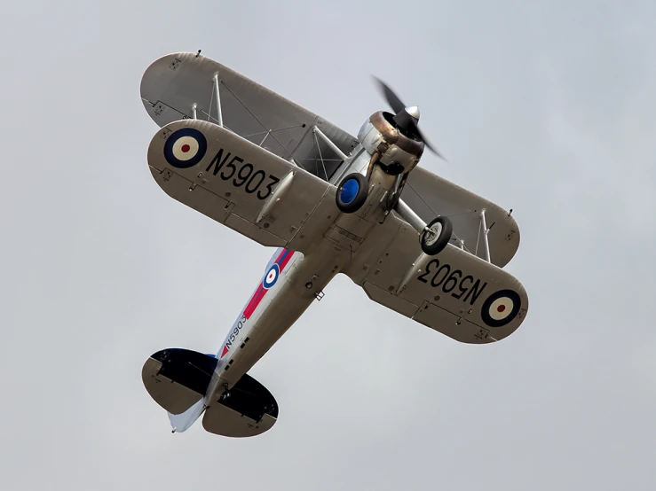 an old fashioned plane in flight with a propeller