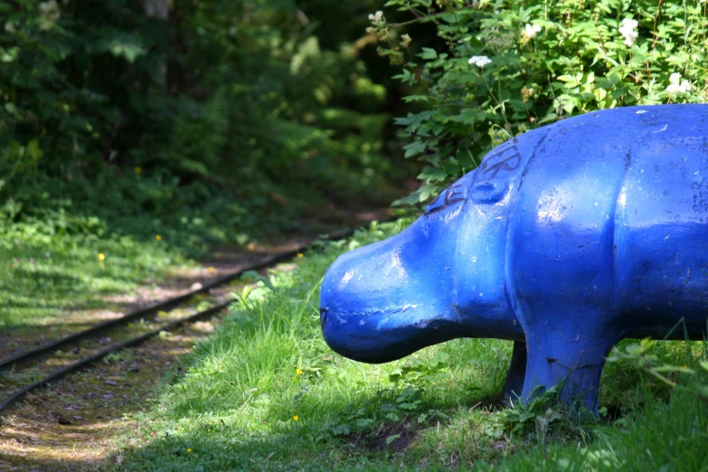 an animal like bench on some grass near tracks