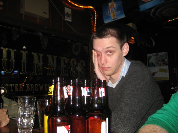 a man sitting in front of a bar next to bottles