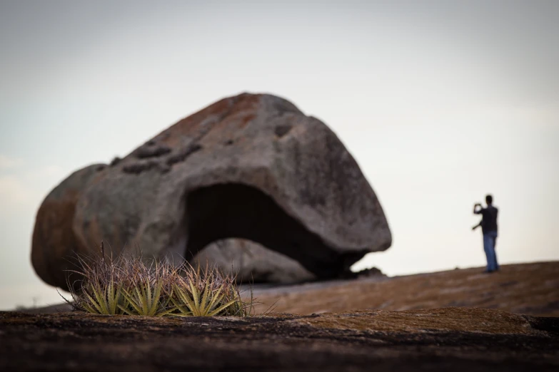 the person standing by the rock is taking a picture