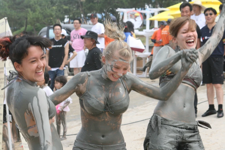 three girls covered in mud in a crowd