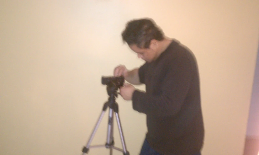 a man holding a camera next to a small tripod