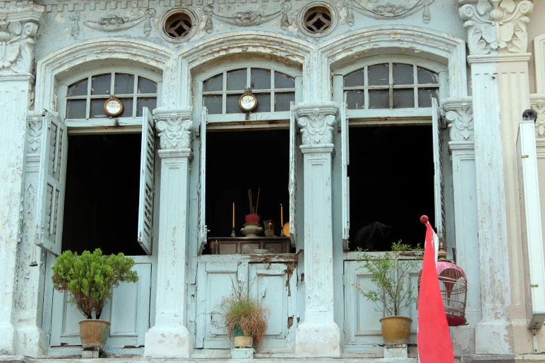 a white building with three windows and a red cone in front of the window